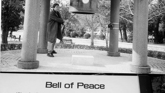 Man ringing large Bell of Peace inJ